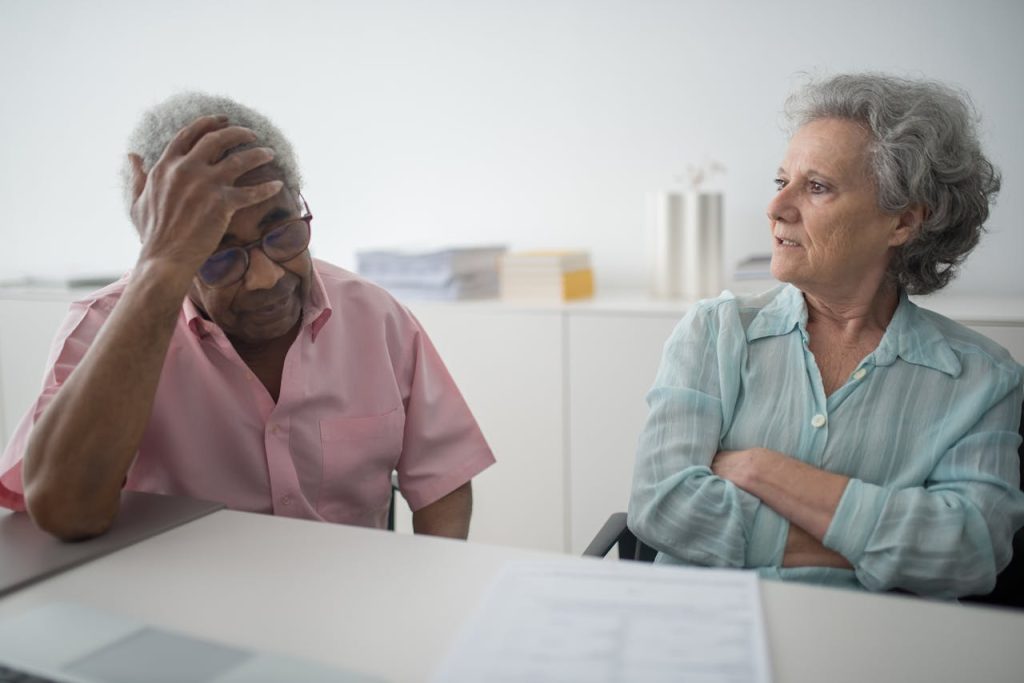 who-we-are Senior couple engaged in a thoughtful conversation indoors, expressing emotions and contemplation.